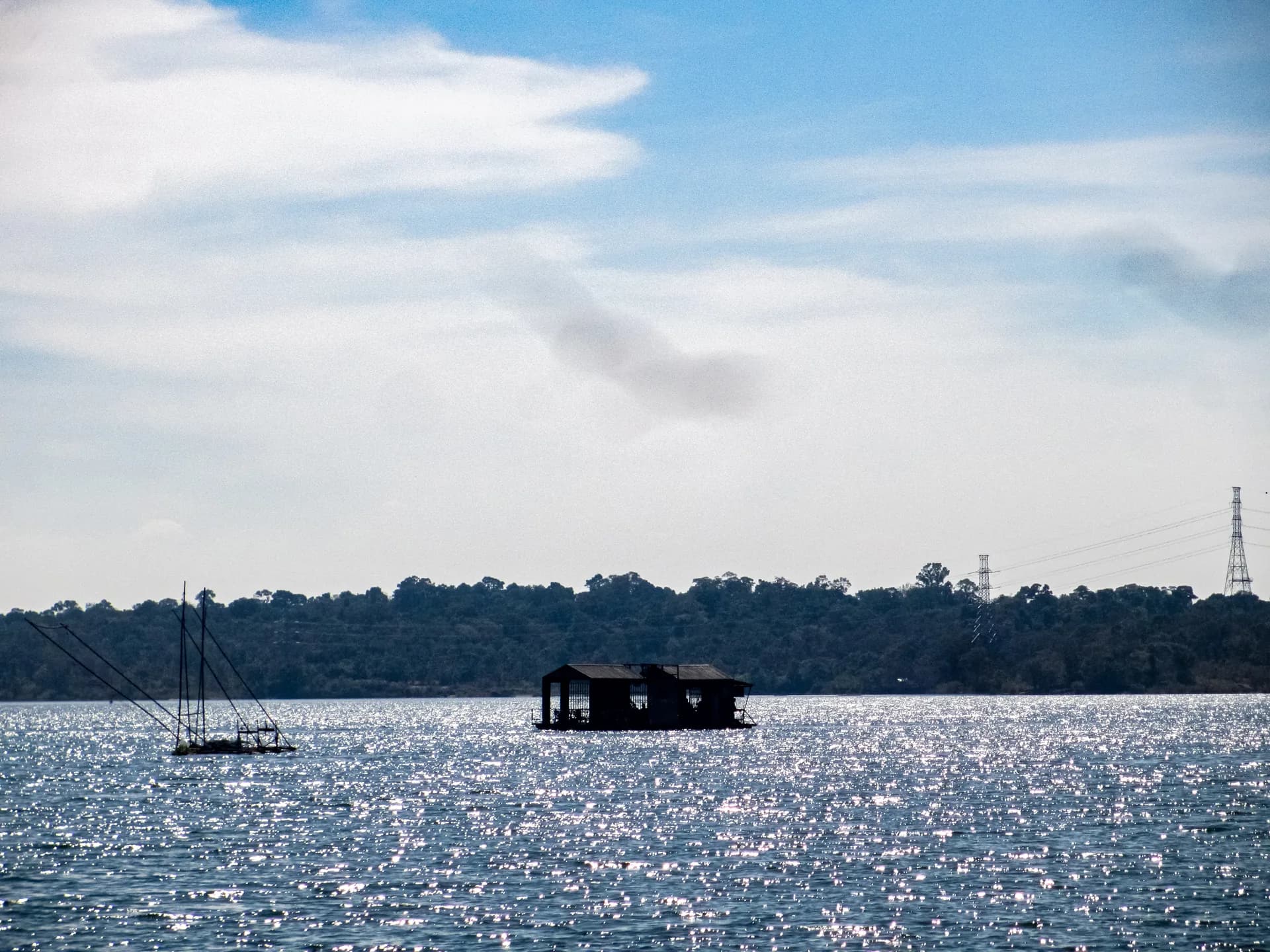 Fishing rigs and a floating shelter silhouetted on a sunlit lake